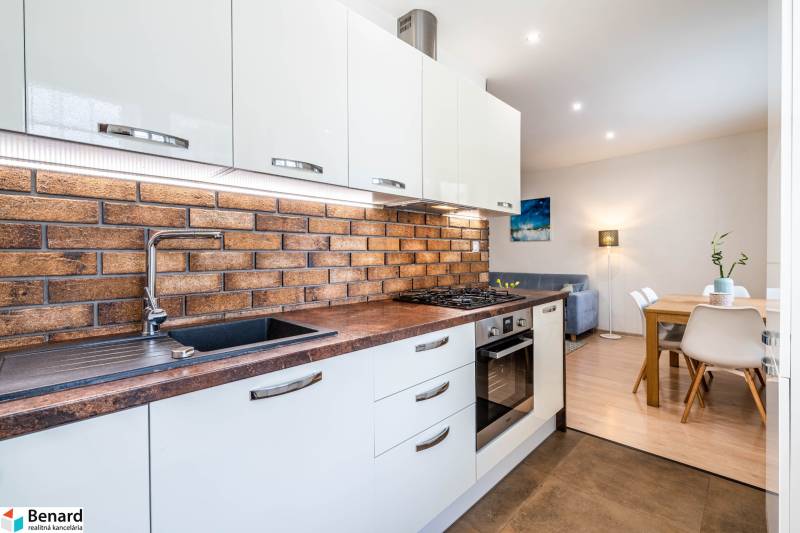 Kuchyně v 3-pokojovém bytě s cihlovým obkladem na stěně a podlahou s dřevěným dekorem.