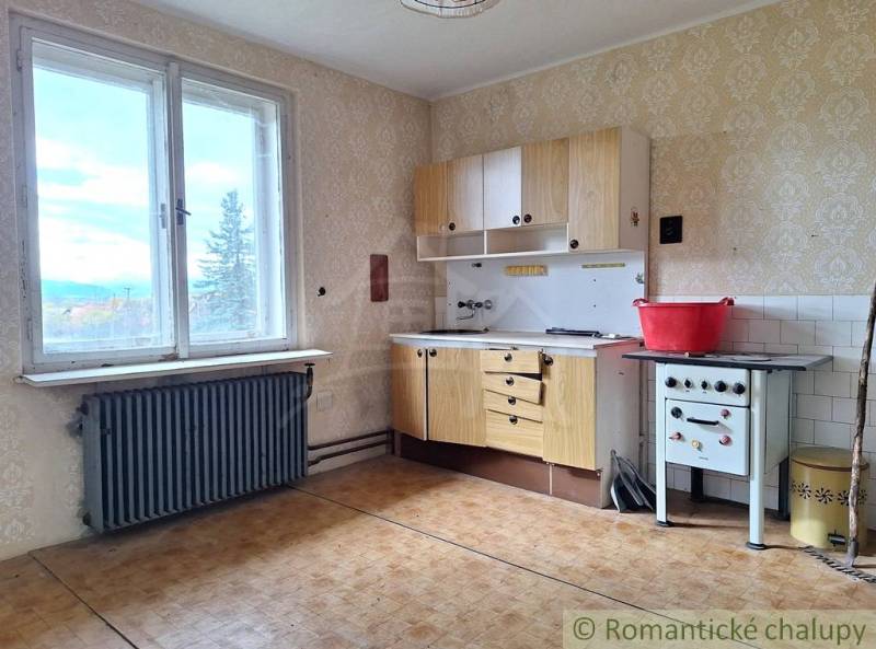 Kuchyně v rodinném domě s retro sporákem, podlahou s dřevěným dekorem a výhledem.