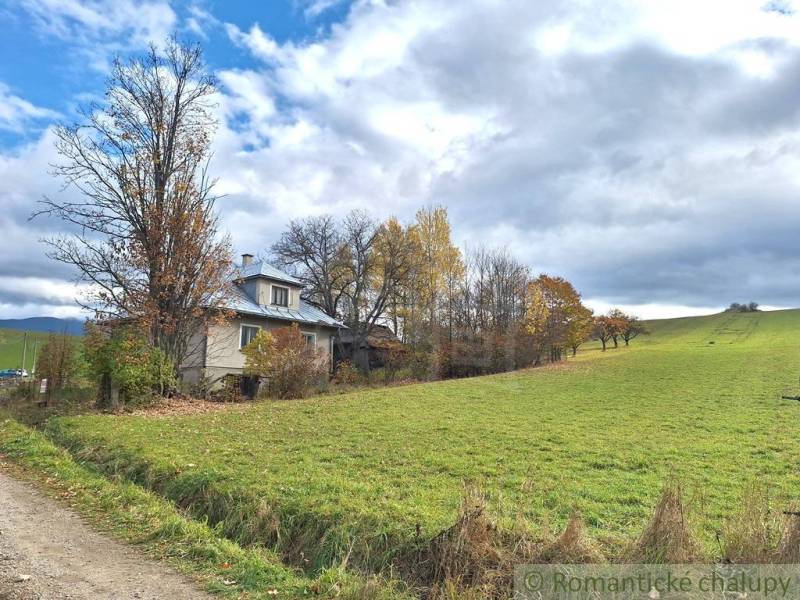 Rodinný dům v Liptovských Beharovcích obklopený přírodou a podzimními stromy na okraji louky.