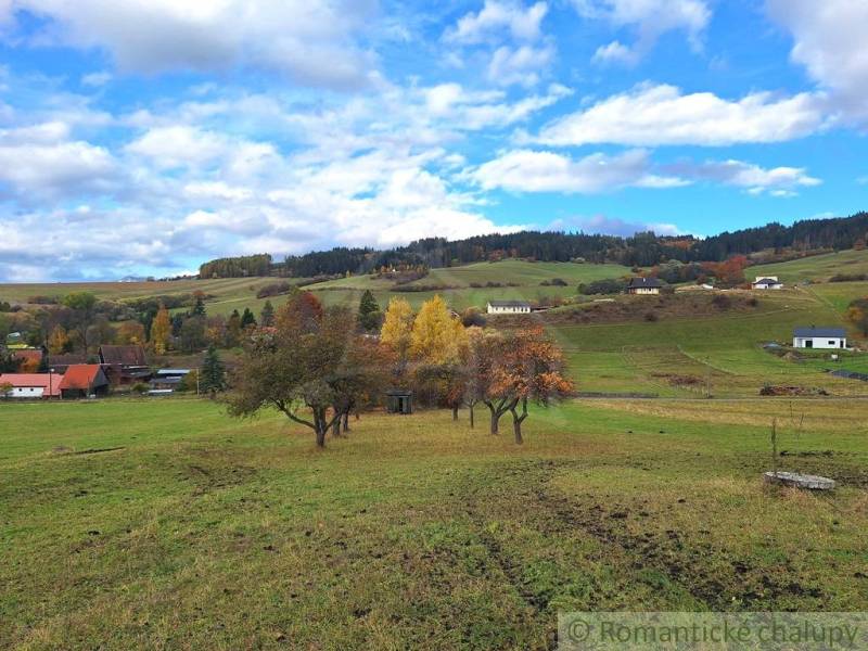 Krajina v Liptovských Beharovcích s ovocnými stromy a rodinnými domy v pozadí.