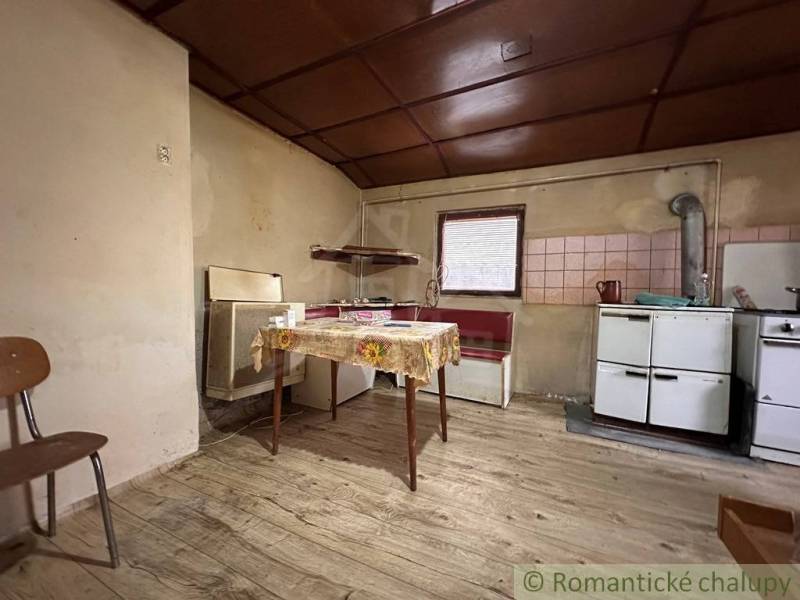 Kuchyně v rodinném domě s podlahou s dřevěným dekorem a jednoduchým vybavením.