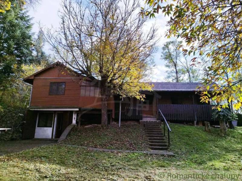 Chata v Dudincích obklopená stromy a svěží zelení, ideální na odpočinek.