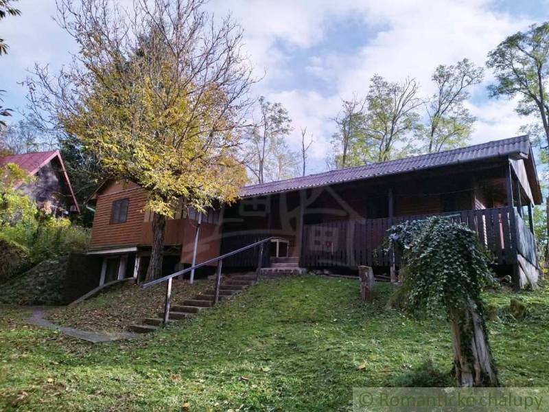 Chata v Dudincích obklopená přírodou s terasou a stromy na dvoře.