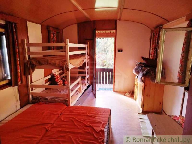 Interiér chaty se čtyřmi postelemi a prosvětleným výhledem na terasu.