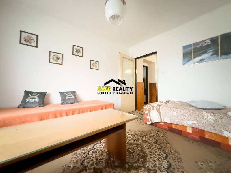 Obývací pokoj v rodinném domě s kobercem a kresbami na stěně.