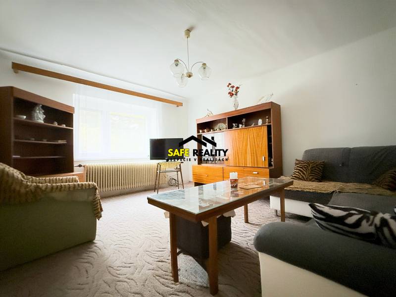 Obývací pokoj v rodinném domě s pohovkami, skříňkami a stolkem, kobercem na podlaze.