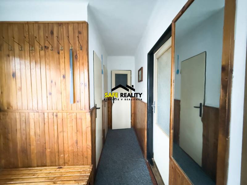 Vstupní chodba v rodinném domě s dřevěným obkladem a zrcadlem na stěně.