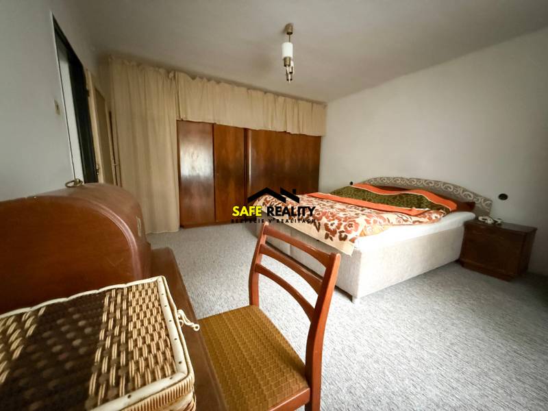 Ložnice v rodinném domě s kobercem, postelí a skříní.