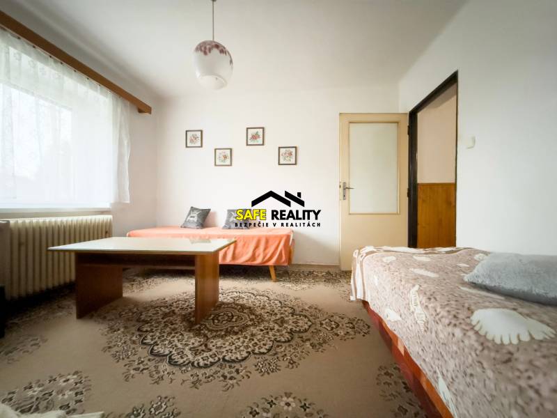 Obývací pokoj v rodinném domě se dvěma pohovkami a stolem na koberci.