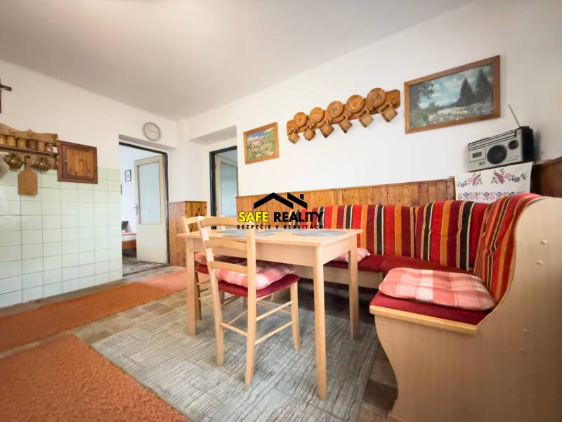 Jídelna rodinného domu s rohovou lavicí, dřevěným dekorem a dekorativními obrázky na stěně.