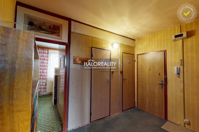 Vstupní chodba v 3-pokojovém bytě s dřevěnou dekorací a vzorovaným kobercem.