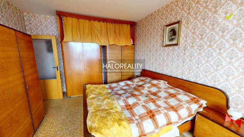 Ložnice ve 3pokojovém bytě s dekorační tapetou a dřevěným nábytkem.