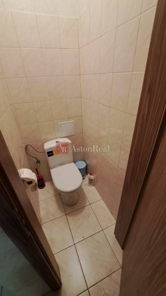 Koupelnové obchodní prostory s dlažbou, toaletou a příslušenstvím.