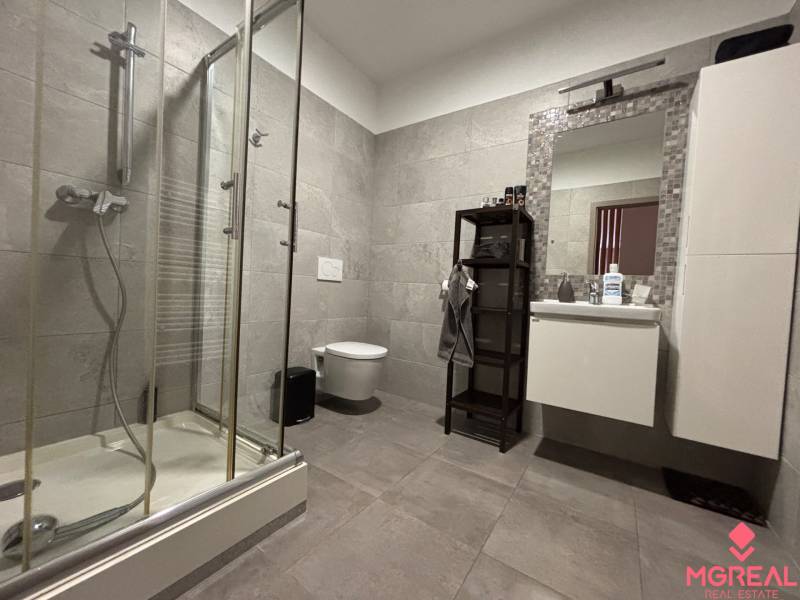 Koupelna dvoupokojového bytu s moderním sprchovým koutem a prostorem pro hygienické potřeby.