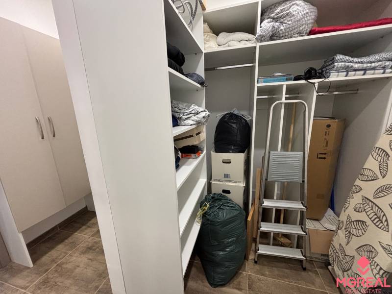 Úložný prostor v 2-pokojovém bytě s regály, schůdky a krabicemi.