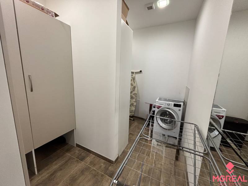 Výklenek s pračkou, sušákem a skříní v 2-pokojovém bytě; podlaha s dřevěným dekorem.