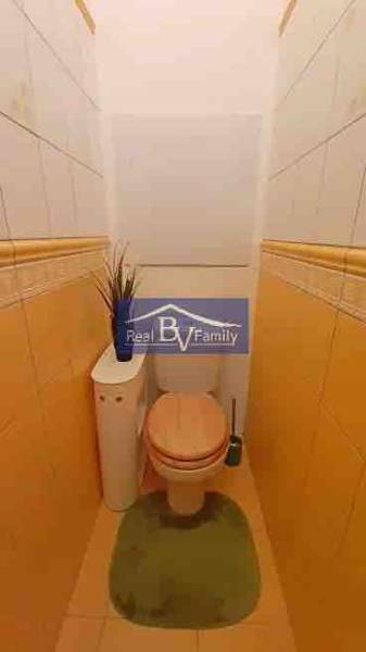 Toaleta s béžovými stěnami a kachličkami v 2-pokojovém bytě s dekorací.