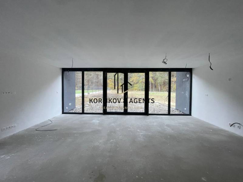 Prostorná místnost s velkými okny v rodinném domě, výhled do zahrady.