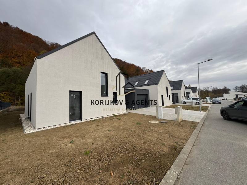 Rodinný dům na ulici Pod Drieňovou v Kamenici nad Cirochou, řadová zástavba s auty.