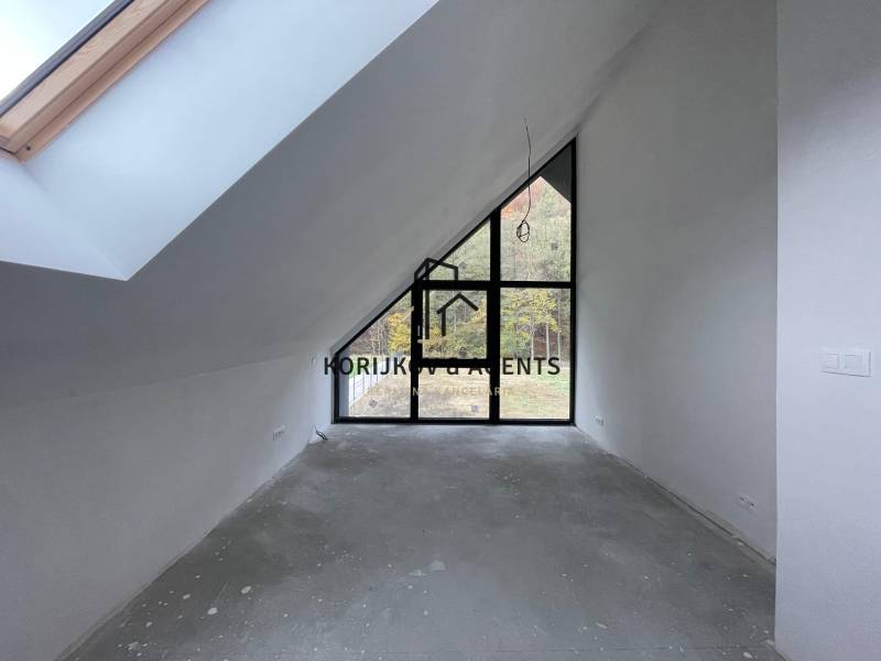 Podkrovní pokoj s velkými okny a vyvýšeným stropem v rodinném domě, bez podlahové krytiny.