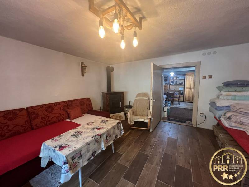 Pohodlný pokoj v chatě s útulným posezením, krbem a dřevěným stropem.