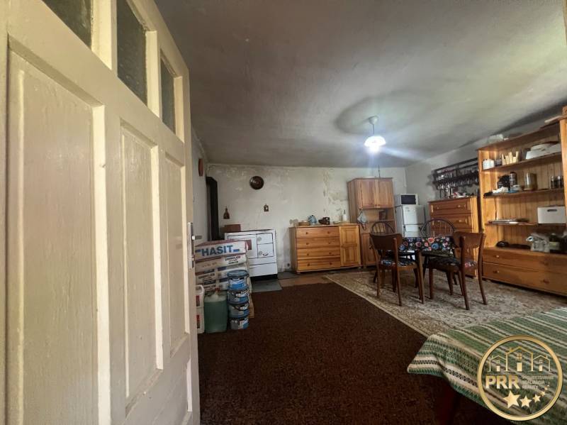 Interiér s dřevěným nábytkem, kobercem, stolem a chata dodává rustikální atmosféru.