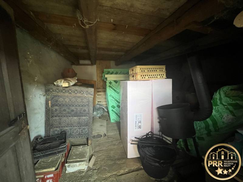 Skladovací prostor na chatě v Šípkově s dekorativní pecí a různými boxy.