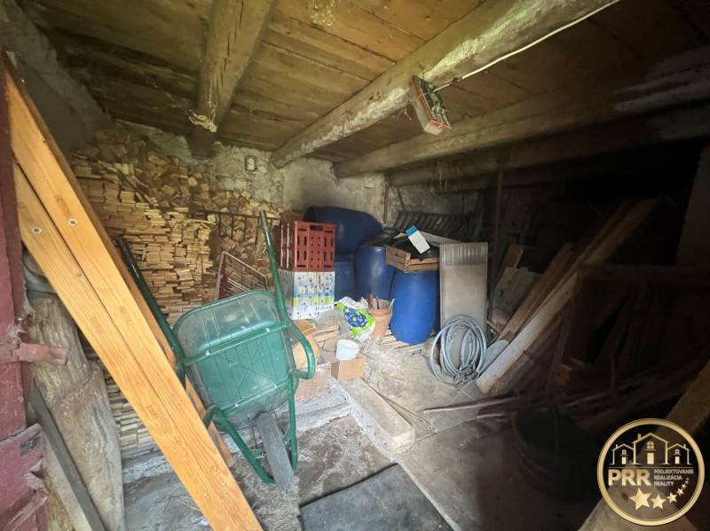 Dřevěná chata se zásobami dřeva, barely a nářadím. Rustikální podkroví vhodné k uskladnění.