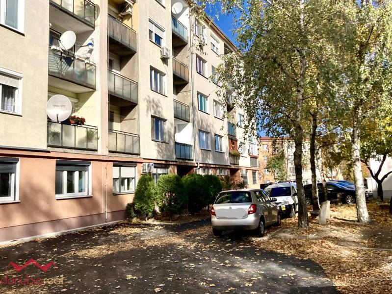 Bytový dům na Mederčské v Komárně se zaparkovanými auty a stromy.