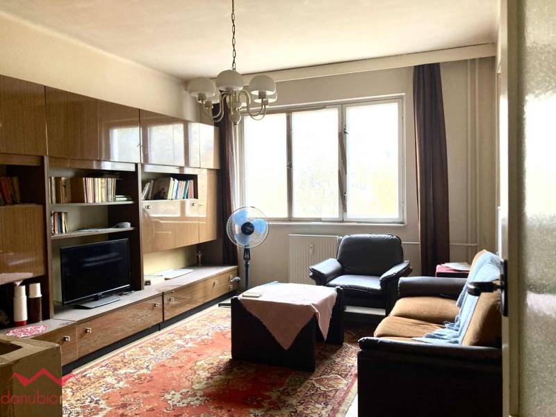 Obývací pokoj v 3pokojovém bytě s nábytkem, koberec a velké okno.