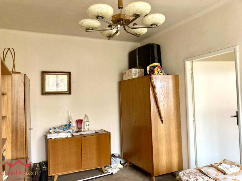 Pokoj v 3-pokojovém bytě s dřevěným nábytkem a dekorativním lustrem.