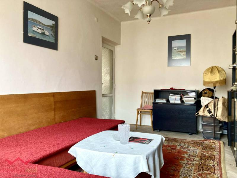 Obývací pokoj v 3pokojovém bytě s pohovkou, kobercem a dekorativními obrázky na stěně.