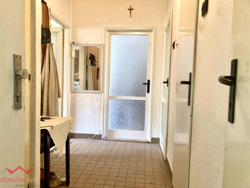 Chodba v 3-pokojovém bytě s dlažbou, zrcadlem a plátěným stolem.