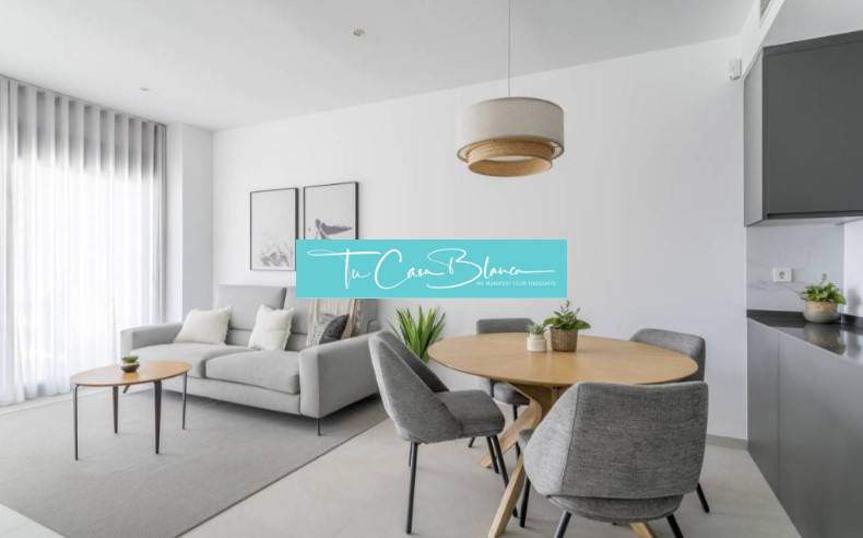 Světlý obývací pokoj rekreačního apartmánu se šedým křeslem a dřevěným stolem.