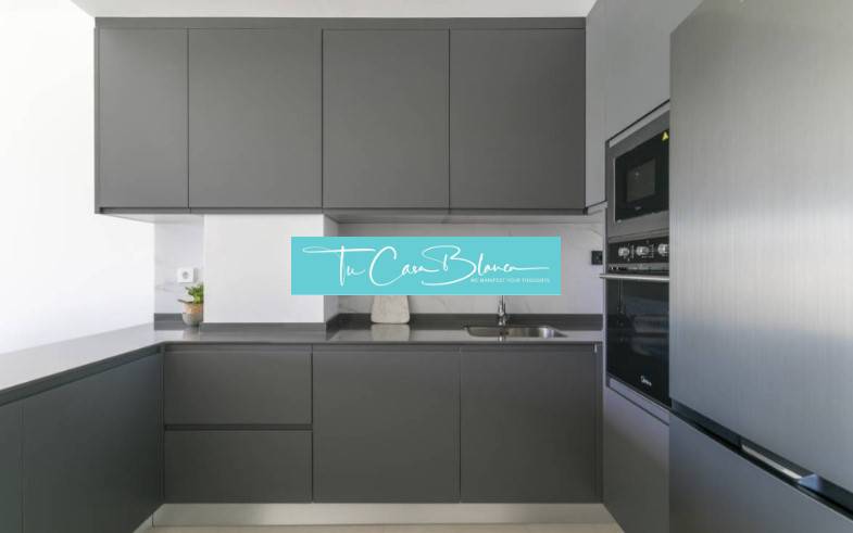 Kuchyně v rekreačním apartmánu s tmavými skříňkami a vestavěnými spotřebiči.