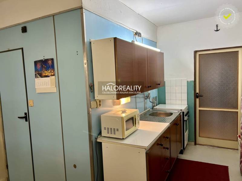 Kuchyně s dřevěnými skříňkami a bílými spotřebiči ve 4pokojovém bytě.