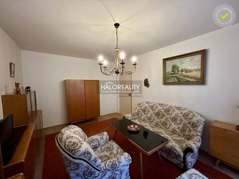 Obývací pokoj ve 4pokojovém bytě s klasickým nábytkem a elegantním lustrem.