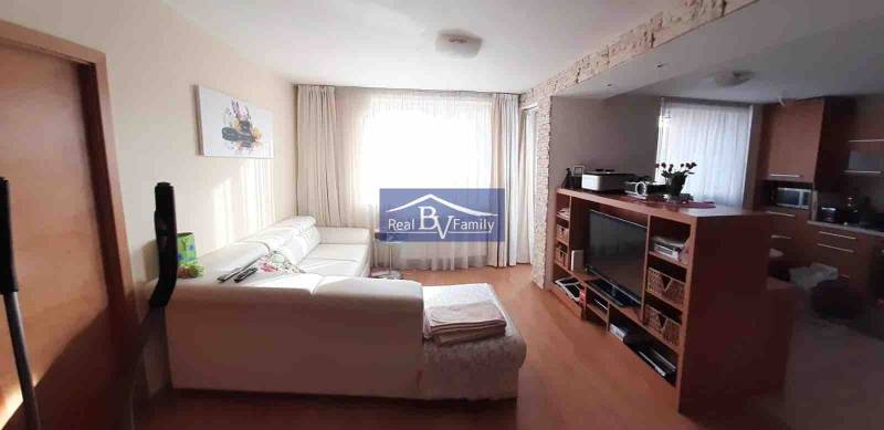 Obývací pokoj s bílou sedačkou a televizorem, podlaha s dřevěným dekorem, 2pokojový byt.