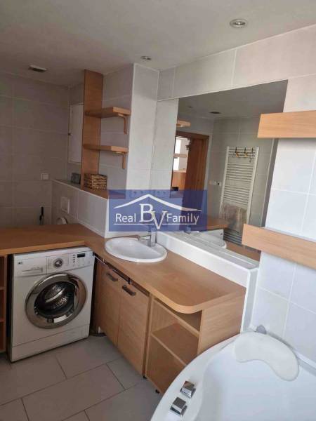 Koupelna v 2-pokojovém bytě s pračkou, umyvadlem a vanou, vybavená dřevěným dekorem.