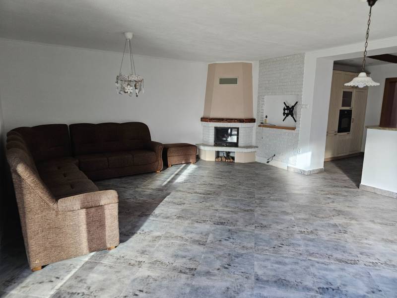 Obývací pokoj v rodinném domě s podlahou s dřevěným dekorem a rohovou pohovkou.