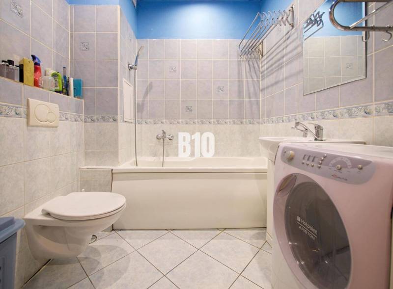 Koupelna v 2-pokojovém bytě se sprchovým koutem, umyvadlem a pračkou.