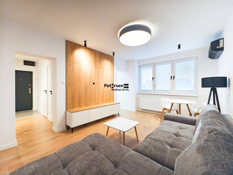 Obývací pokoj s pohovkou, jídelním stolem, dřevěnou podlahou v 2pokojovém bytě.