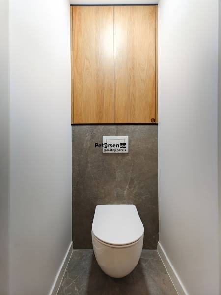 Koupelna v 2-pokojovém bytě s podlahou z tmavého kamene a dřevěnými skříňkami.