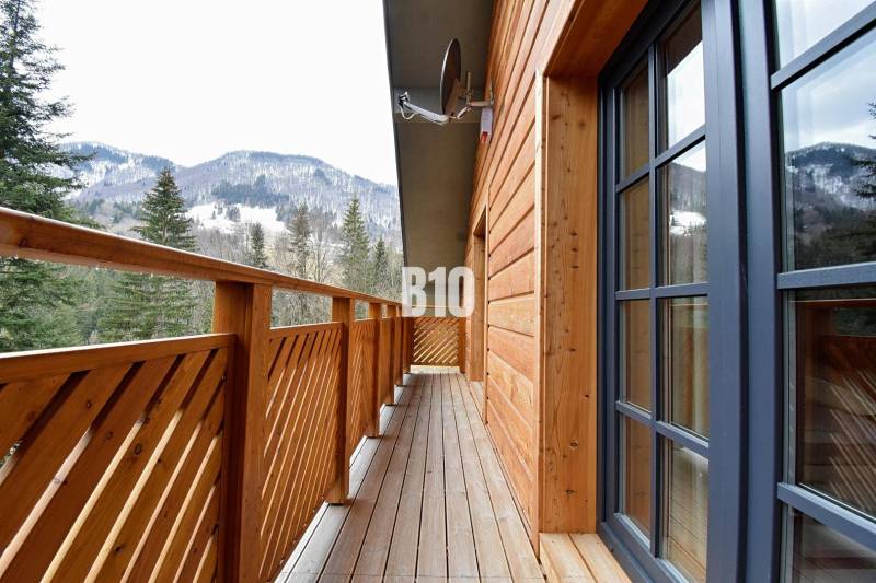 Balkon chaty v Terchové s výhledem na zasněžené hory a lesy.