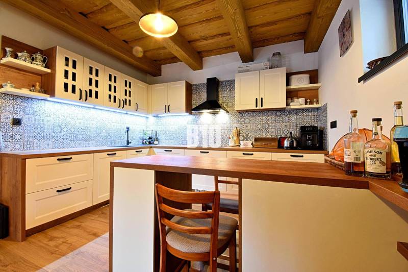 Kuchyně v chatě s dřevěným stropem, podlahou s dřevěným dekorem a modrými obklady.