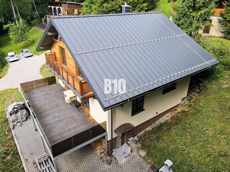 Chata v Terchové se šikmou střechou, velkou terasou a dřevěnými detaily.