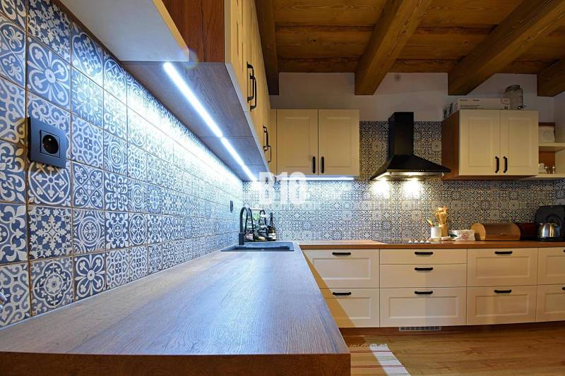 Kuchyně v chatě s dlaždicemi a podlahou s dřevěným dekorem, osvětlená LED světly.