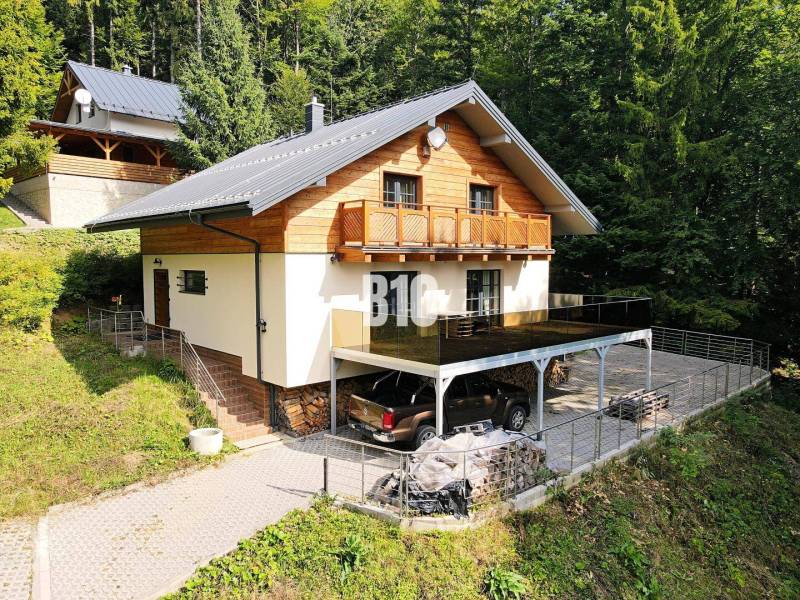 Chata v Terchové obklopená lesem s parkovací plochou a terasou.