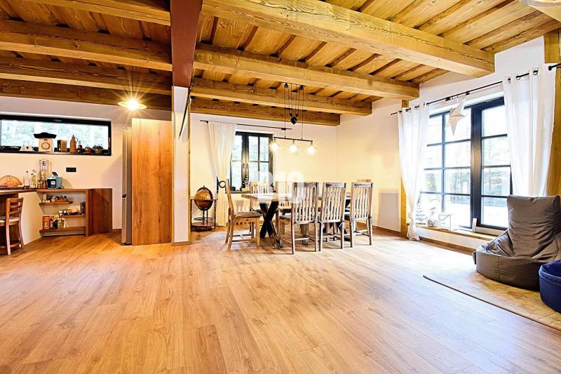 Otevřený interiér v chatě s podlahou s dřevěným dekorem a jídelním stolem.