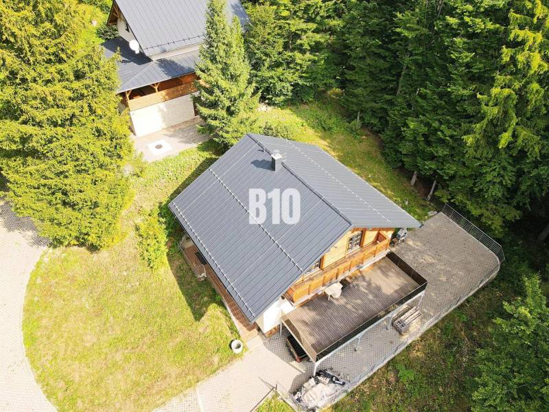 Chata v Terchové obklopená lesem s dřevěnou terasou a přilehlou zahradou.